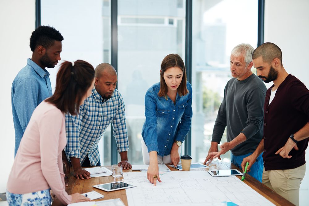people-standing-around-table-getty-508385344.jpg