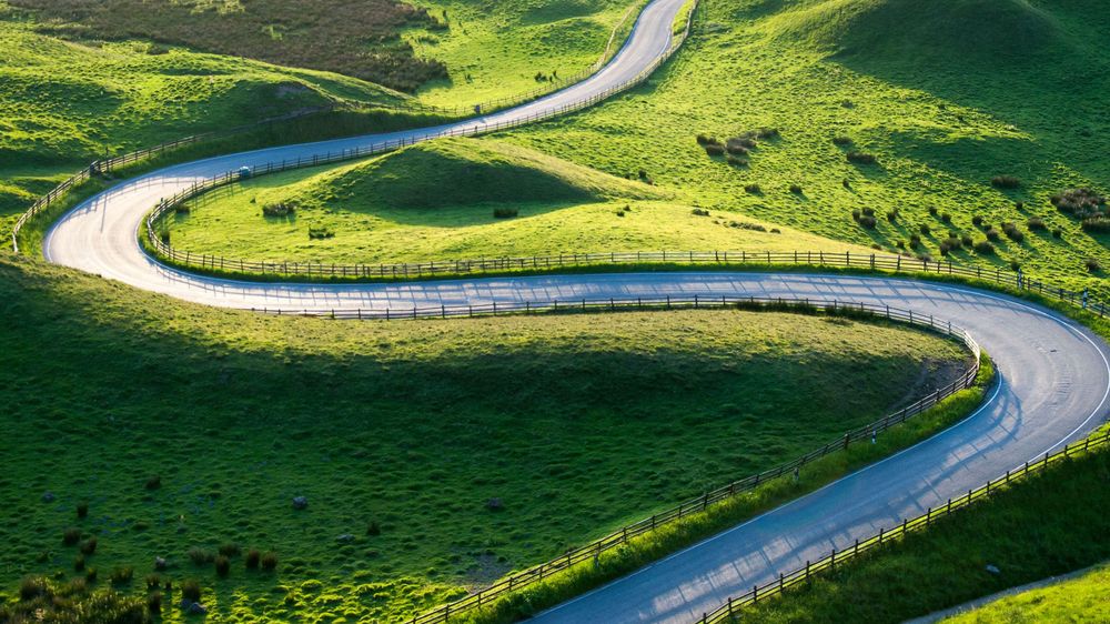 winding-road-grassy-landscape-summer-fields-in-the-uk--getty-513199459.jpg